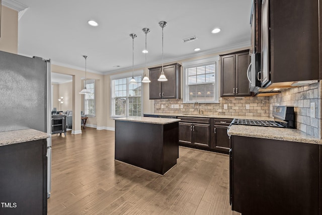 kitchen featuring stainless steel appliances, a kitchen island, light hardwood / wood-style floors, and decorative light fixtures