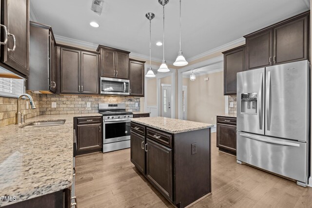 kitchen with pendant lighting, sink, light hardwood / wood-style floors, a kitchen island, and stainless steel appliances