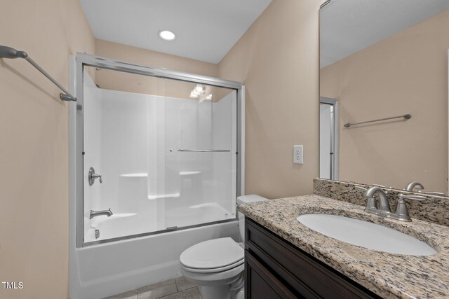 full bathroom with tile patterned floors, vanity, toilet, and bath / shower combo with glass door