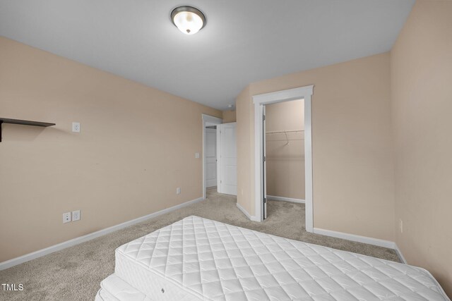 bedroom with a spacious closet, a closet, light carpet, and lofted ceiling