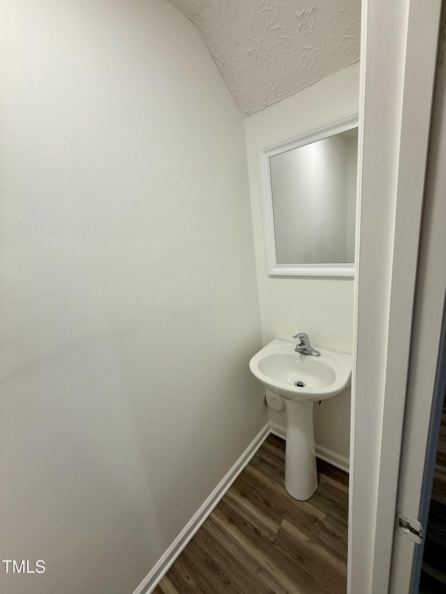 bathroom featuring lofted ceiling, sink, wood-type flooring, and a textured ceiling