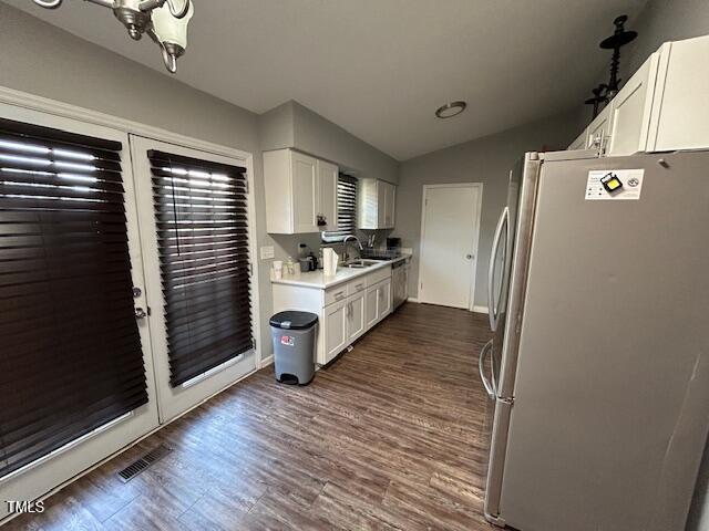 kitchen featuring vaulted ceiling, dark wood-type flooring, sink, white cabinets, and stainless steel refrigerator