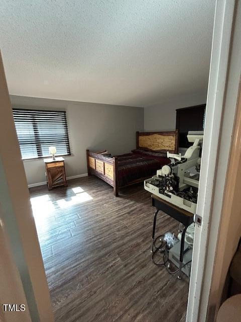 bedroom with dark hardwood / wood-style floors and a textured ceiling