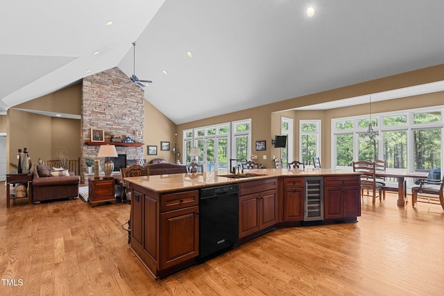 kitchen with dishwasher, beverage cooler, a fireplace, a center island with sink, and light wood-type flooring