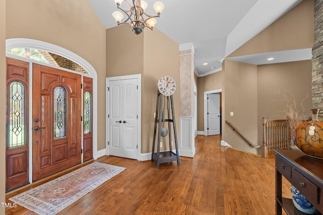 foyer entrance featuring a notable chandelier, wood-type flooring, and high vaulted ceiling