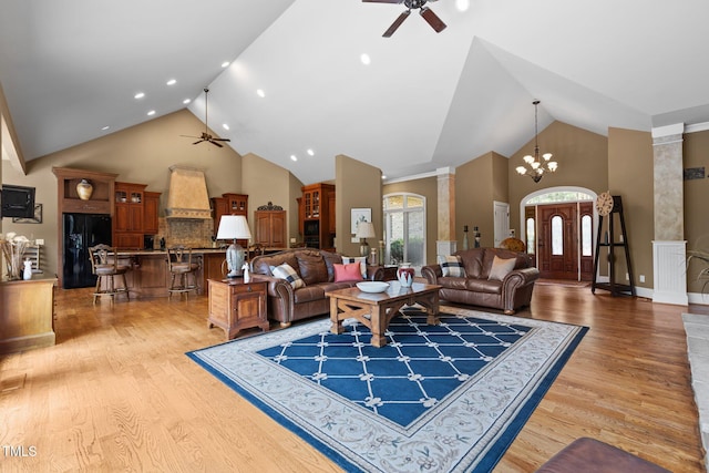 living room featuring ornate columns, high vaulted ceiling, wood-type flooring, and ceiling fan with notable chandelier