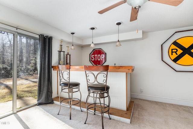 bar with ceiling fan, a healthy amount of sunlight, light colored carpet, and decorative light fixtures