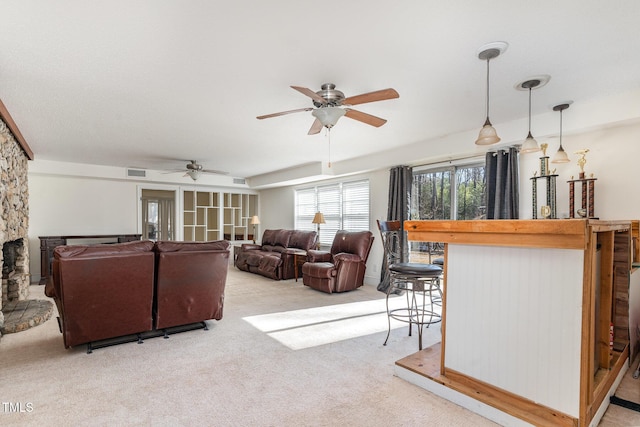 carpeted living room with ceiling fan, french doors, and a stone fireplace