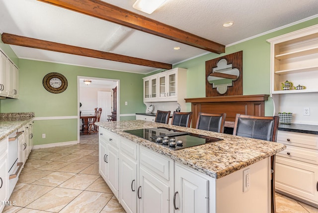 kitchen featuring a textured ceiling, a center island, white cabinetry, black electric stovetop, and light stone counters