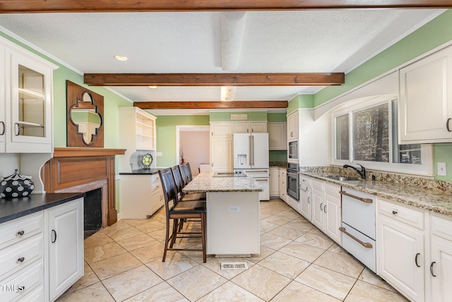 kitchen featuring a center island, beam ceiling, sink, white cabinetry, and appliances with stainless steel finishes