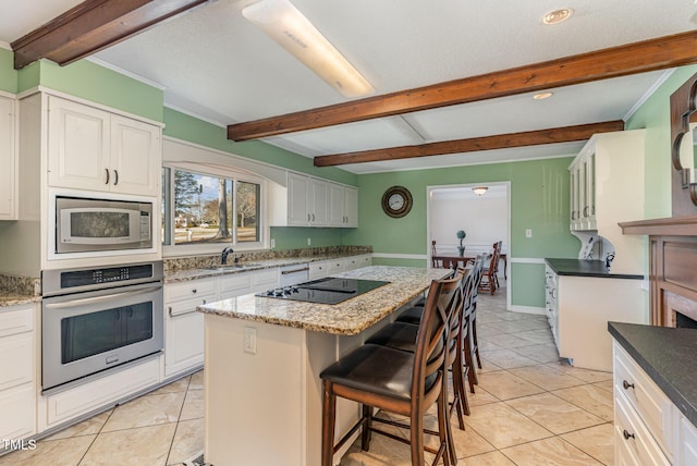 kitchen with light tile patterned floors, white cabinetry, appliances with stainless steel finishes, and a center island