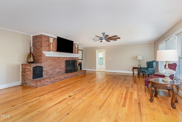 living room featuring ceiling fan, a fireplace, ornamental molding, and light hardwood / wood-style flooring