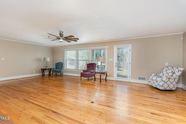 living area with light wood-type flooring, ceiling fan, and crown molding