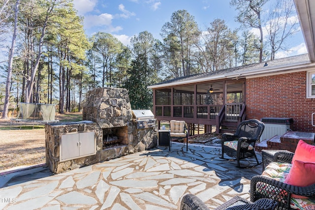 view of patio with exterior fireplace, a sunroom, central AC unit, and a trampoline