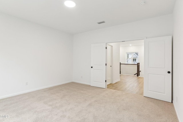 unfurnished room featuring light carpet and baseboards