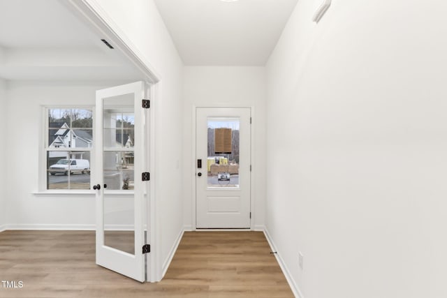 doorway to outside with light wood-style flooring and baseboards