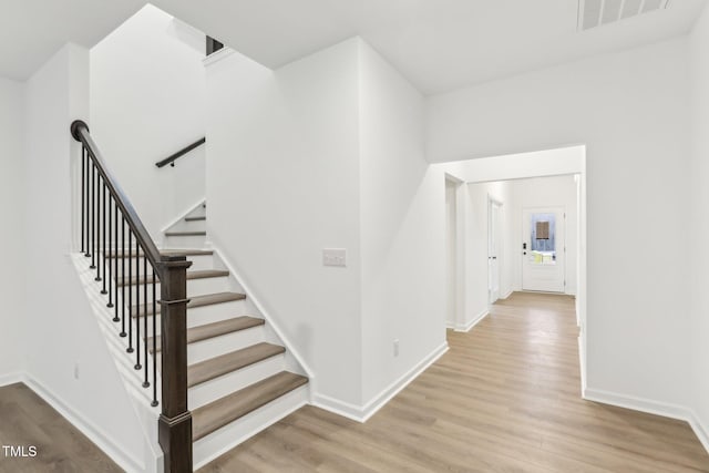 stairs with wood finished floors, visible vents, and baseboards