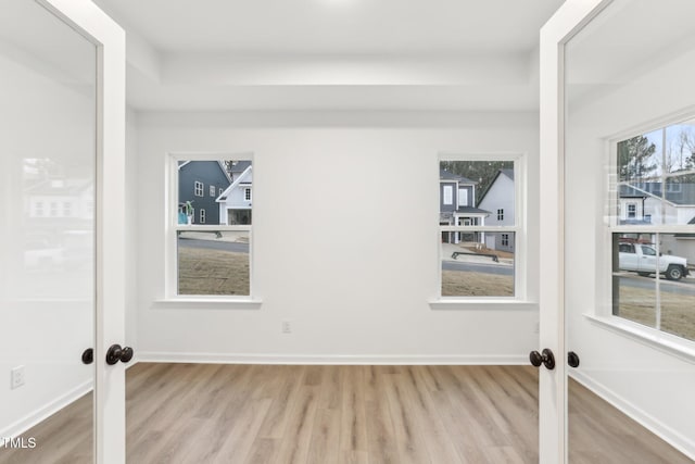 spare room with light wood finished floors, baseboards, and french doors