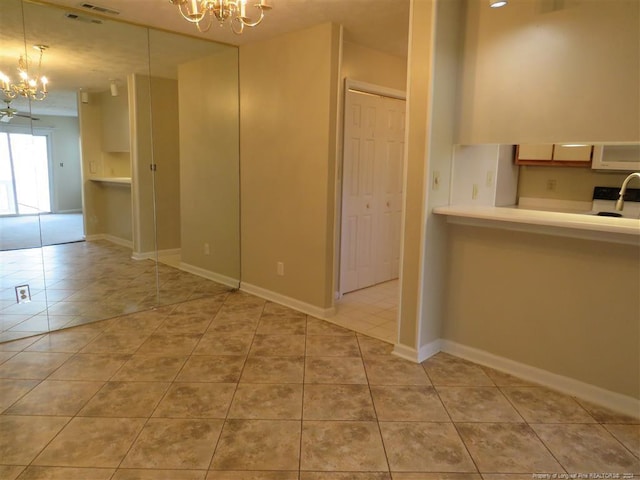 unfurnished room with light tile patterned floors, a notable chandelier, and sink