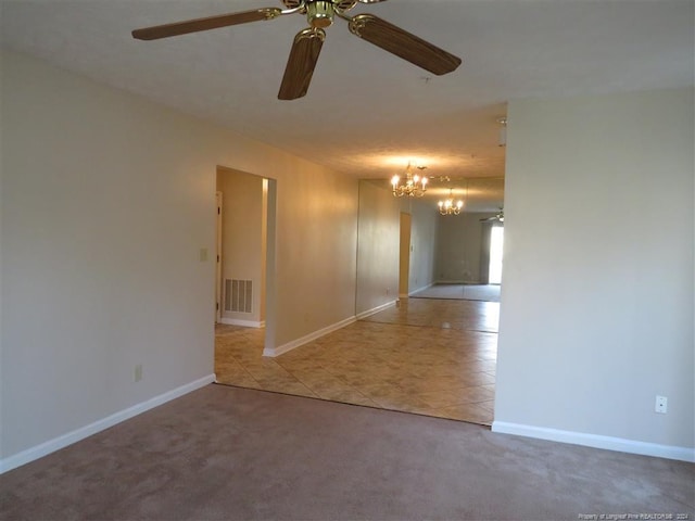 carpeted spare room featuring ceiling fan with notable chandelier