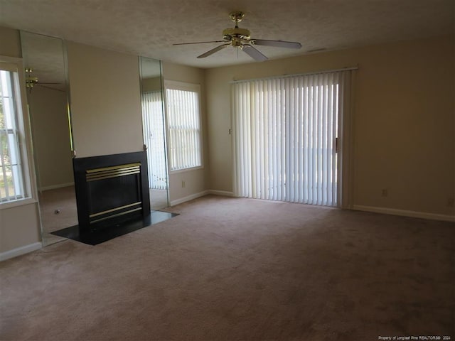 unfurnished living room with carpet flooring, ceiling fan, and a wealth of natural light