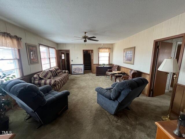 living room featuring a textured ceiling, ceiling fan, and carpet floors