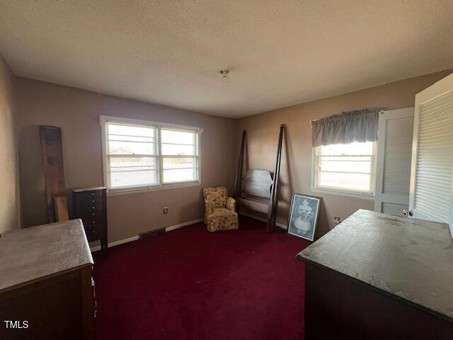 interior space featuring dark carpet and a textured ceiling