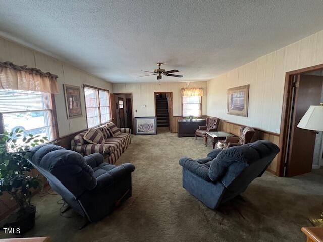 carpeted living room with a textured ceiling and ceiling fan