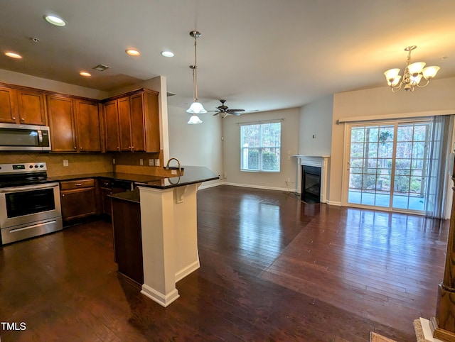 kitchen featuring kitchen peninsula, dark hardwood / wood-style floors, stainless steel appliances, and decorative light fixtures