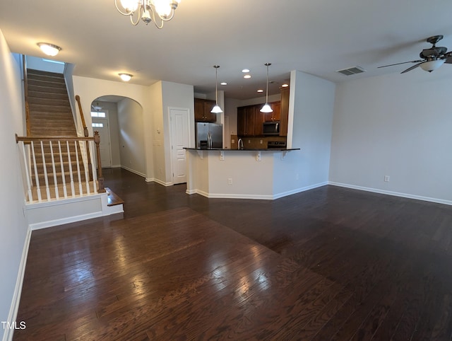 unfurnished living room featuring dark hardwood / wood-style flooring and ceiling fan with notable chandelier