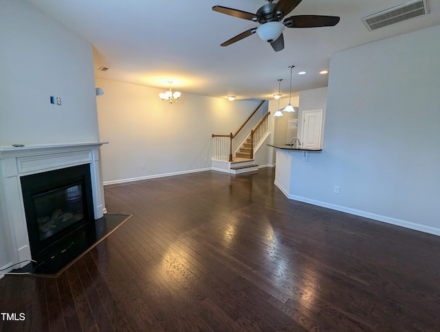 unfurnished living room featuring dark hardwood / wood-style floors, sink, and ceiling fan with notable chandelier