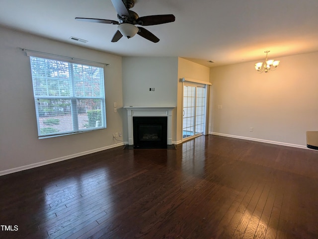 unfurnished living room featuring ceiling fan with notable chandelier and dark hardwood / wood-style floors