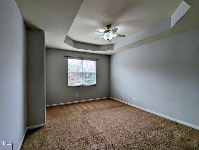 empty room featuring carpet, ceiling fan, and a tray ceiling