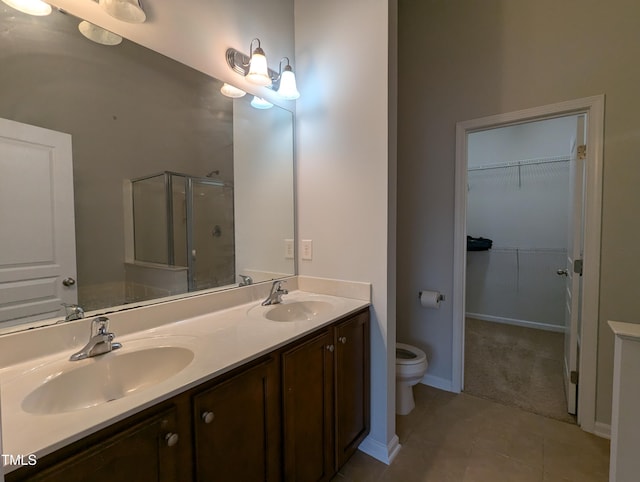 bathroom featuring tile patterned flooring, vanity, toilet, and walk in shower