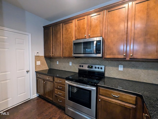 kitchen with tasteful backsplash, dark stone countertops, dark hardwood / wood-style floors, and appliances with stainless steel finishes