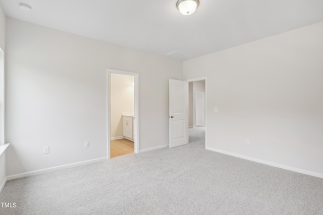 unfurnished bedroom featuring light colored carpet and connected bathroom