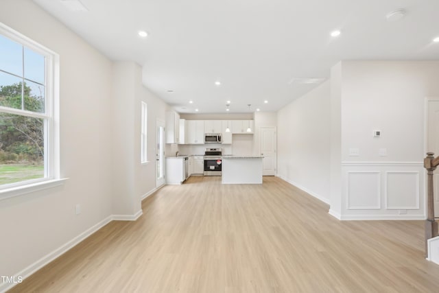 unfurnished living room featuring plenty of natural light and light hardwood / wood-style flooring