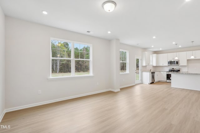 unfurnished living room with a healthy amount of sunlight and light hardwood / wood-style floors