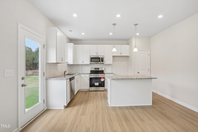 kitchen featuring white cabinets, pendant lighting, stainless steel appliances, and plenty of natural light