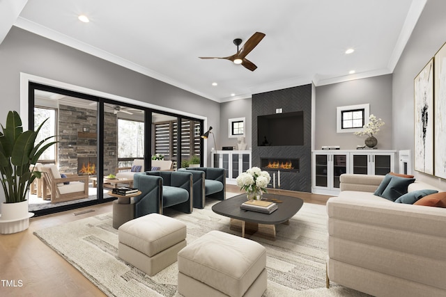 living room featuring light hardwood / wood-style flooring, crown molding, a fireplace, and ceiling fan