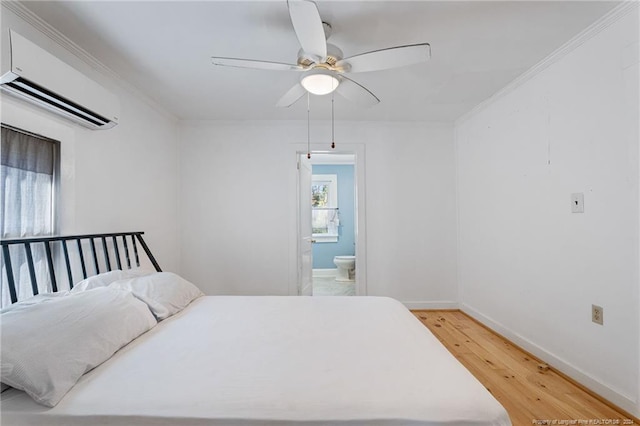 bedroom with connected bathroom, ceiling fan, a wall mounted air conditioner, crown molding, and wood-type flooring