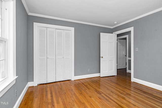 unfurnished bedroom featuring crown molding, a closet, and light hardwood / wood-style flooring