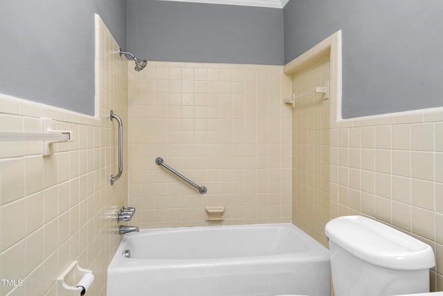 bathroom with tile walls, tiled shower / bath, and toilet