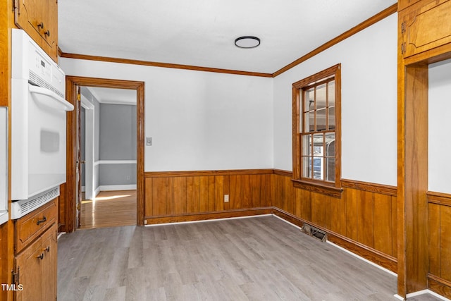 empty room with crown molding and light hardwood / wood-style flooring