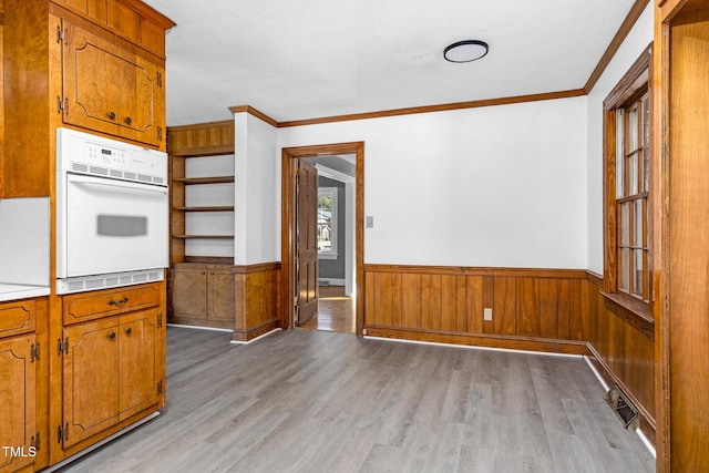 kitchen with crown molding, light hardwood / wood-style floors, and white oven