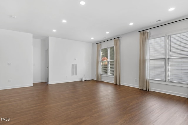 spare room with plenty of natural light and dark hardwood / wood-style flooring