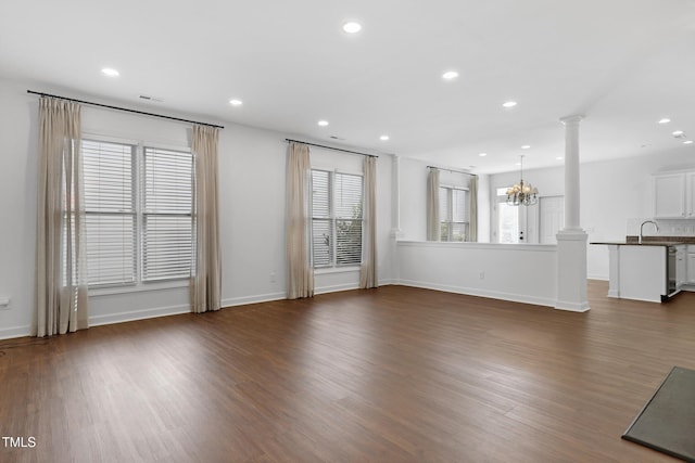 unfurnished living room with a chandelier, dark hardwood / wood-style flooring, and a wealth of natural light