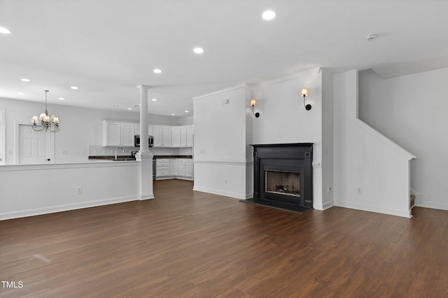 unfurnished living room featuring a notable chandelier, sink, and dark wood-type flooring