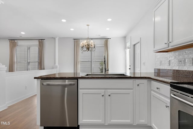 kitchen featuring backsplash, white cabinetry, sink, and stainless steel dishwasher