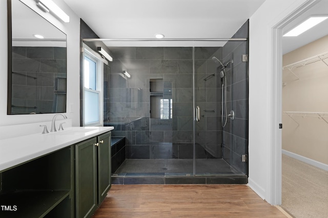 bathroom with wood-type flooring, vanity, and a shower with shower door